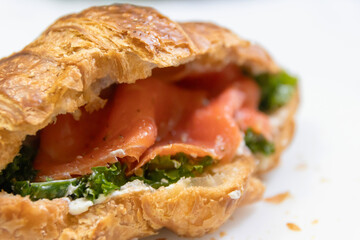 A delicious croissant filled with smoked salmon and fresh greens, perfect for a gourmet breakfast or brunch.