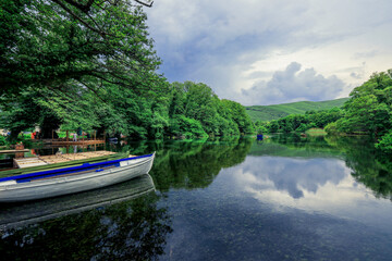 Fototapeta premium Tranquil waters of Ohrid Macedonia reflecting green trees and serene skies on a peaceful afternoon