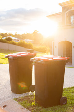 Sun flare over two garbage bins on the curb outside home