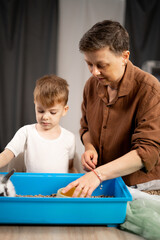 Mother and son cleaning rabbit cage together at home