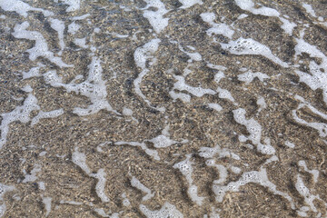 Foamy Ocean Water over Pebbled Shoreline Close-Up