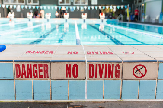 danger no diving sign on the tiles of a public swimming pool