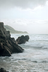 Ocean waves gently crashing against rugged rocky formations on a serene beach with lush greenery in the background under a soft, cloudy sky