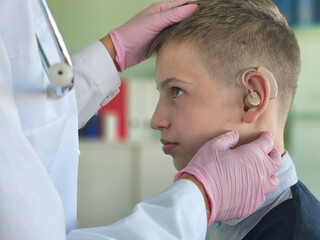 Fototapeta premium A pediatric audiologist fitting a young boy with a hearing aid in a medical office