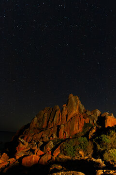 A light-painting long exposure of Castle Rock jutting out into the sea.