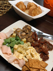 a white plate with different types of cheese, dried tomatoes, hams decorated with mushrooms