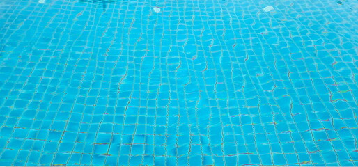 Ripple water in blue pool. The pool is tiled with blue ceramic tiles. The rippling water in the pool gives the floor a wavy appearance. Blue water serface. Blue ocean rippled water texture reflection.