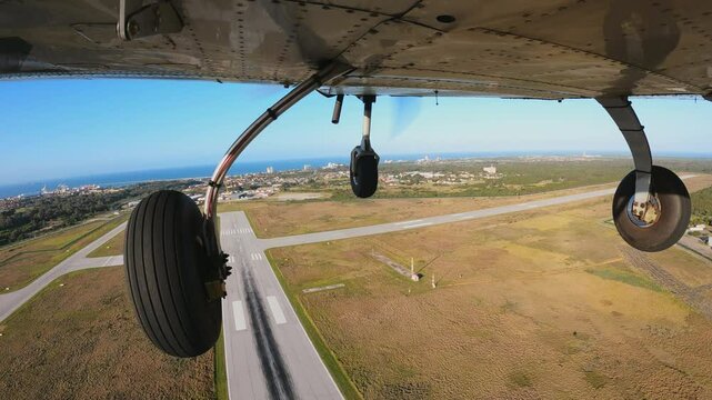 Light three wheels airplane flying over the runway. Climb after take off for training flight. View from the bottom of the aircraft.