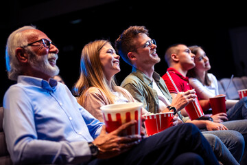 Grandfather with his grandchildren in the cinema watching the movie.