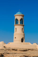 Obraz premium Historic watchtower overlooking the coastline of Sur Oman on a clear sunny day showcasing traditional architecture and blue skies