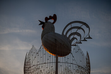Big rooster monument in evening on dark blue sky as symbol for chickens, roosters, and Easter...