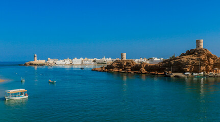 A serene view of Sur Oman showcasing traditional boats and stunning coastal architecture under a clear blue sky