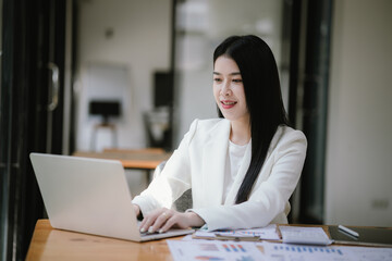 Happy Asian Women's Business Women work at the desk using laptops and calculators to analyze financial data. About the growth of financial and accounting organizations