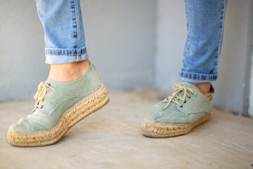 Pair of green espadrille shoes with jute sole and rolled-up jeans