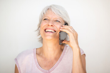 Mature woman smiling during phone call on white background