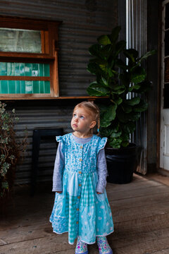 Little girl in blue dress looking up with worried expression