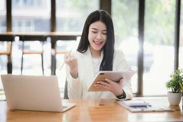 Obraz premium Beautiful Asian businesswoman focused on reviewing documents in a modern office.