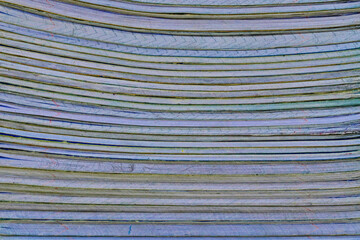 .Close-up of a large stack of books with horizontal lines running through them. The papers are stacked to create a repeating pattern.