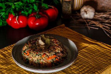 Spanish rice, uzbek pilaf hot dish with meat and vegetables, rustic table kitchen decoration with ingredients, yellow textile cloth, parcley, dill
