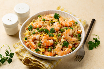Close up of white bowl with homemade prawns or shrimp fried rice with fried eggs, vegetables,...