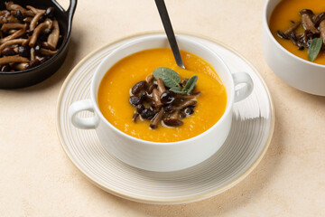 Eating Homemade vegan soup with pumpkin and sauuteed honey fungus or Chiodino edible mushrooms in a white bowl. Autumn meal.