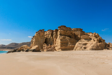 Stunning views of Turtle Beach in Oman showcasing unique rock formations and a serene sandy shoreline under a clear blue sky