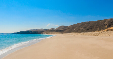 Discovering the serene beauty of Turtle Beach in Oman during a sunny day by the tranquil water\'s edge