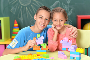 Little brother and sister assemble a construction set at home