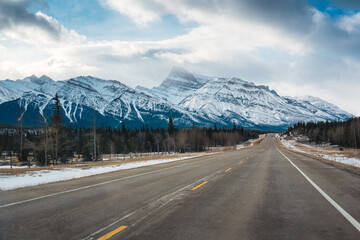 Fototapeta premium Road trip with on highway road with snow covered rocky mountains in winter at Kootenay plains area, Canada
