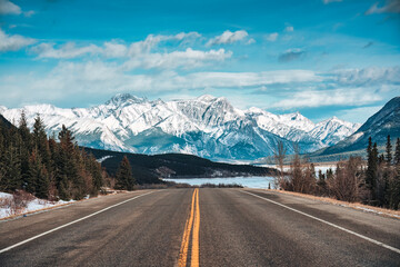 Road trip with on highway road with snow covered rocky mountains in winter at Kootenay plains area, Canada