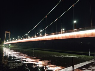 A suspension bridge with lighting. Suspension bridge on the embankment. Night promenade.