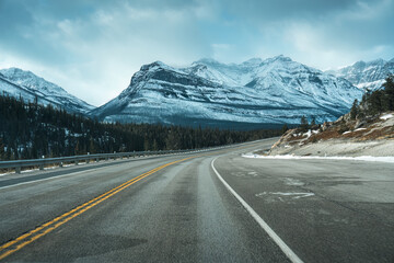Naklejka premium Road trip with on highway road with snow covered rocky mountains in winter at Kootenay plains area, Canada