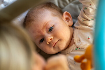 Curious baby gazing up adoringly at a caregiver, with soft lighting and gentle colors.