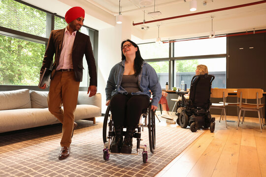 Businessman wearing Sikh turban and businesswoman on wheelchair in office