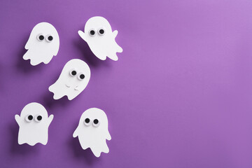 Cute white ghost figures with googly eyes on a purple background. Horizontal Halloween banner. copyspace.