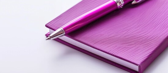 A white background displays a purple notebook and a pink pen viewed from the top ideal for school or office settings with flat lay composition and copy space image
