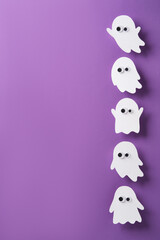 Charming white ghost figure with googly eyes on a purple background. Cute and spooky vertical Halloween banner, place for your text.