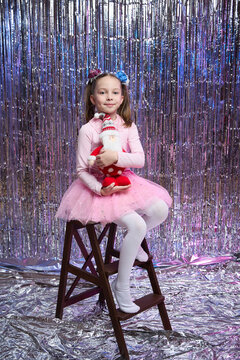 A little girl is sitting in the living room near the Christmas tree with Santa Claus in her hands, New Year's magic