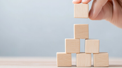 Building tower with wooden blocks showcases creativity and focus. hand carefully places final block, symbolizing growth and achievement