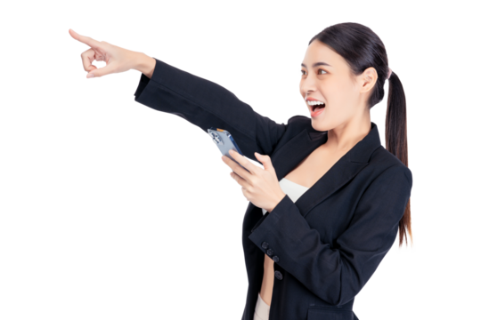 Excited Young Asian business woman points to copy space while holding a smartphone, conveying a sense of excitement and discovery.