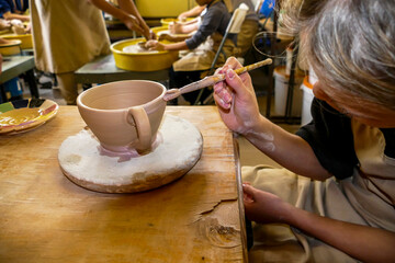 girl's hands paint a cup with a brush, ceramic product, master class, workshop, potter