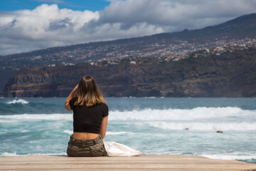 Ragazza di spalle seduta in riva al mare