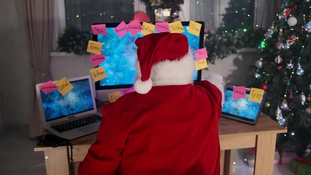 Santa sits at his computer with sticky notes, sipping coffee and racing to finish holiday preparations before the Christmas deadline.