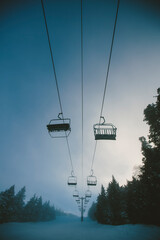 Chairlift at a ski and snowboard resort during winter with fresh white snow, blue sky and misty fog. Killington, Vermont, New England, USA.