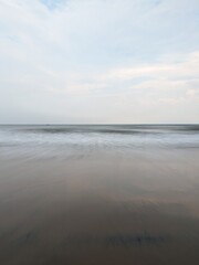 A serene evening at Rushikonda Beach, in Andhra Pradesh, India, with soft golden hues from the setting sun reflecting on the calm, blue waters.