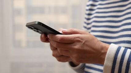 A close-up of hands holding a smartphone at home or work. Woman using smartphone pressing fingerers, reading social media internet, typing text or shopping online.