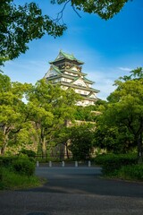 Fototapeta premium Vertical view of Osaka Castle in a beautiful summer sunset, Osaka, Japan by a river