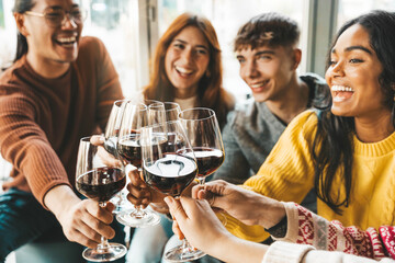 Happy friends drinking red wine sitting at winery bar
