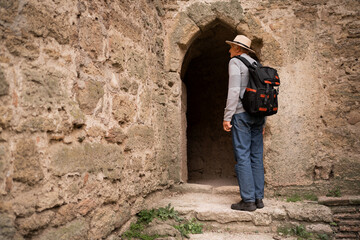 Senior man exploring ancient stone fortress entrance alone