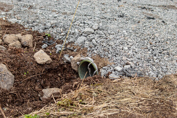 Car entrance through a drainage ditch. Pipe buried in ditch. A road strewn with stones